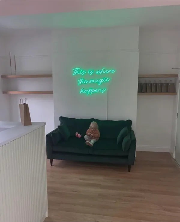 Mint green This is where the magic happens neon sign above a green sofa