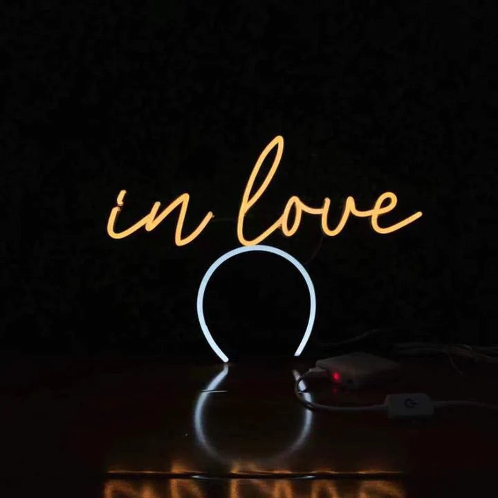 In Love Script neon headband glowing against a dark background
