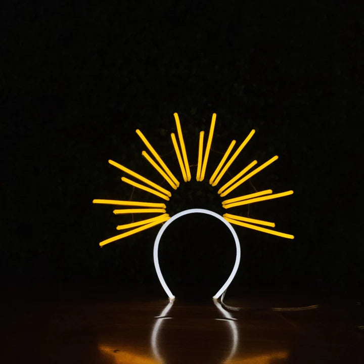 Golden Sunburst neon headband glowing against a dark background